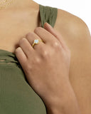 Bague trèfle en argent doré avec pierre claire portée, gros plan