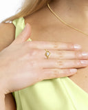 Bague en argent doré sertie d’une pierre claire portée, gros plan