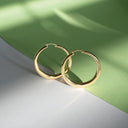 Boucles d’oreilles créoles en argent doré sur fond vert